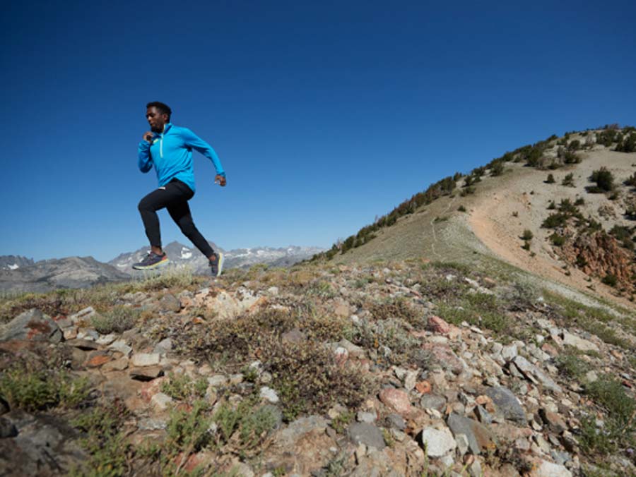 A man running on a trail with a mountain in the background