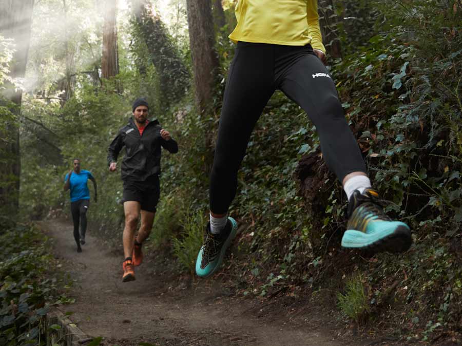 Three people running down a trail.