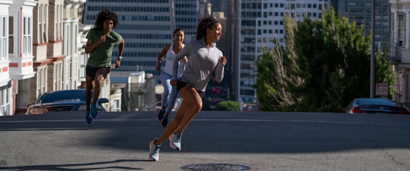 Three people running on a street in a city