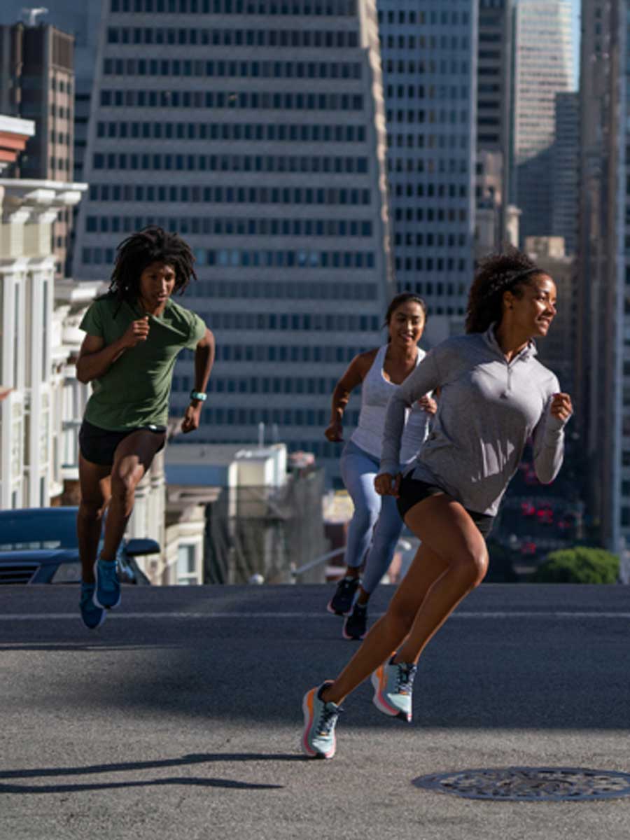 Three people running on a street in a city